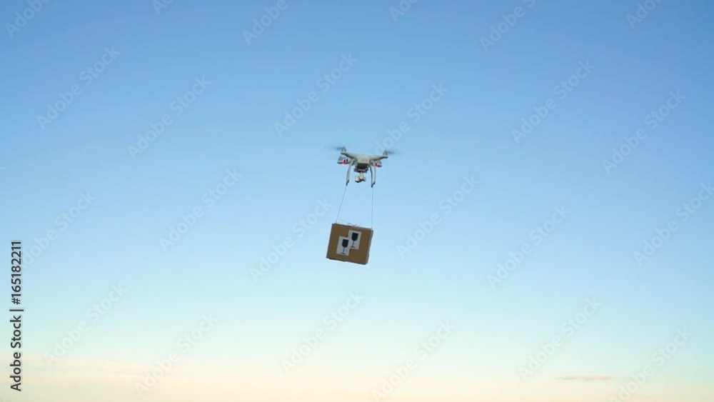 Drone delivering package on the sky background. Slow motion Drone delivering package on the sky background. Slow motion