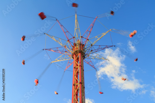 High carousel is whirling on the background of blue sky