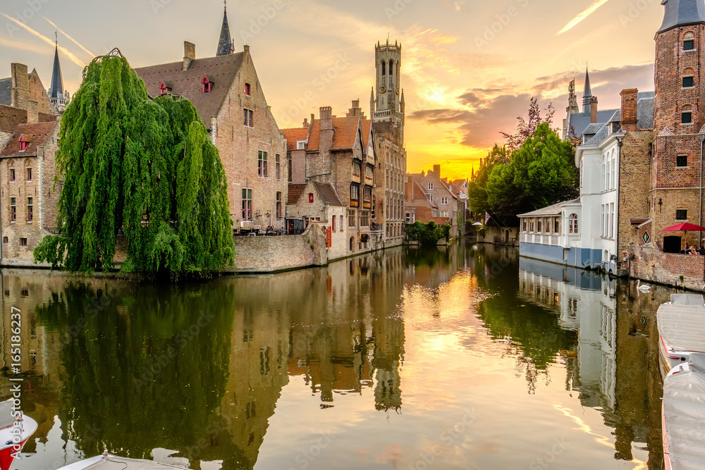 Fototapeta premium Miasto Brugia (Brugge) z kanałem wodnym o zachodzie słońca