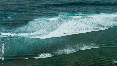 Huge waves rolling one by one to coastline. Surfer try to catch wave. photo