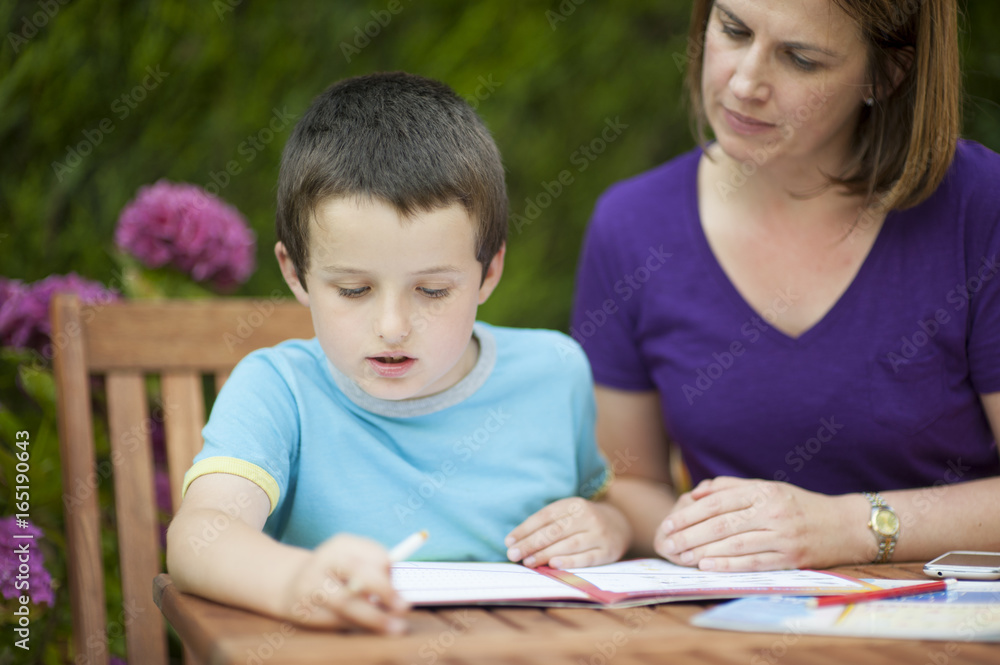 mother or teacher helping her son or pupil with school work mother or teacher helping her son or pupil with school work