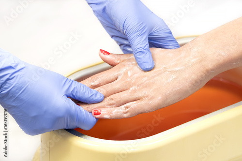 Process paraffin treatment of female hands in beauty salon 