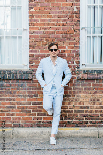 Trendy and stylish man in a seersucker suit standing by a brick wall