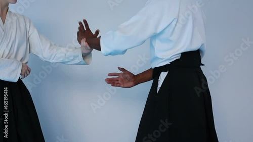 Martial arts master in black hakama practice Aikido with a woman in white kimono
