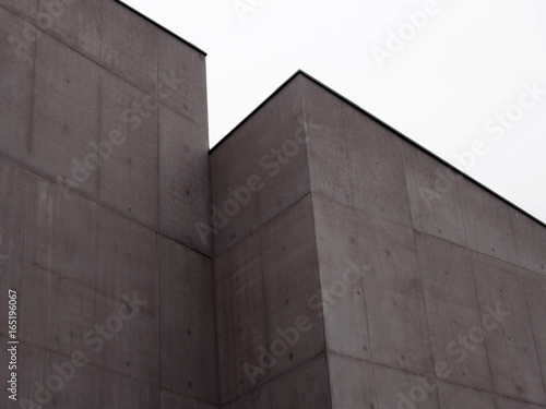 angular stark concrete walls with corners and white sky with rectangualr panels and regular marks