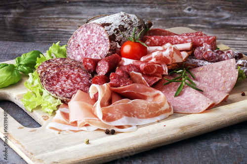 Fototapeta Naklejka Na Ścianę i Meble -  Food tray with delicious salami, pieces of sliced ham, sausage, tomatoes, salad and vegetable - Meat platter with selection