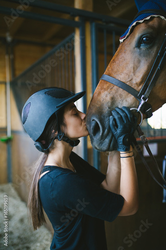 Beautiful brunette girl kissing her horse.  © hedgehog94