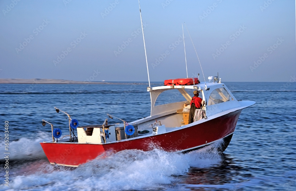 Side and rear view of red recreational fishing boat in Atlantic Ocean. North Carolina.