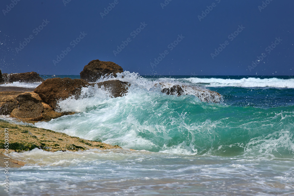 The waves breaking on a stony beach, forming a spray