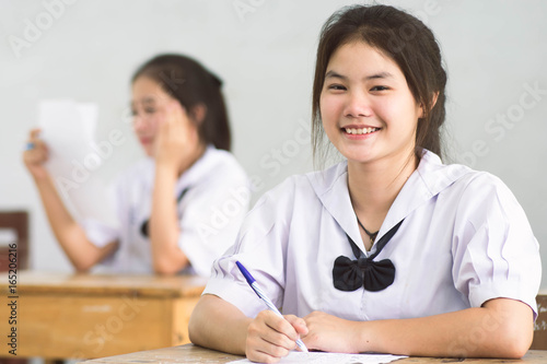 Smile young girl student reading and writing exam with not stress.