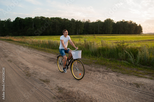 The guy rides a Bicycle along a country road at sunset,