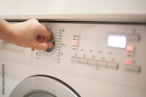Close up of woman choosing program on washing machine