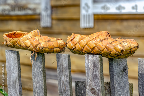 Birch bast shoes hang on fence photo