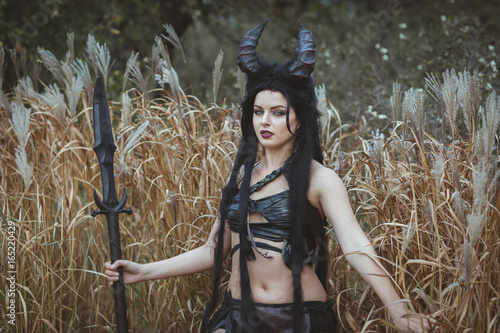 Portrait of a girl with horns stands in the thickets photo