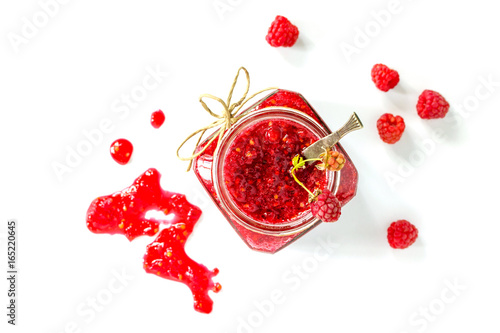 Homemade jam. Glass jar with raspberry jam on a white background. Preserved berry. Top view. photo