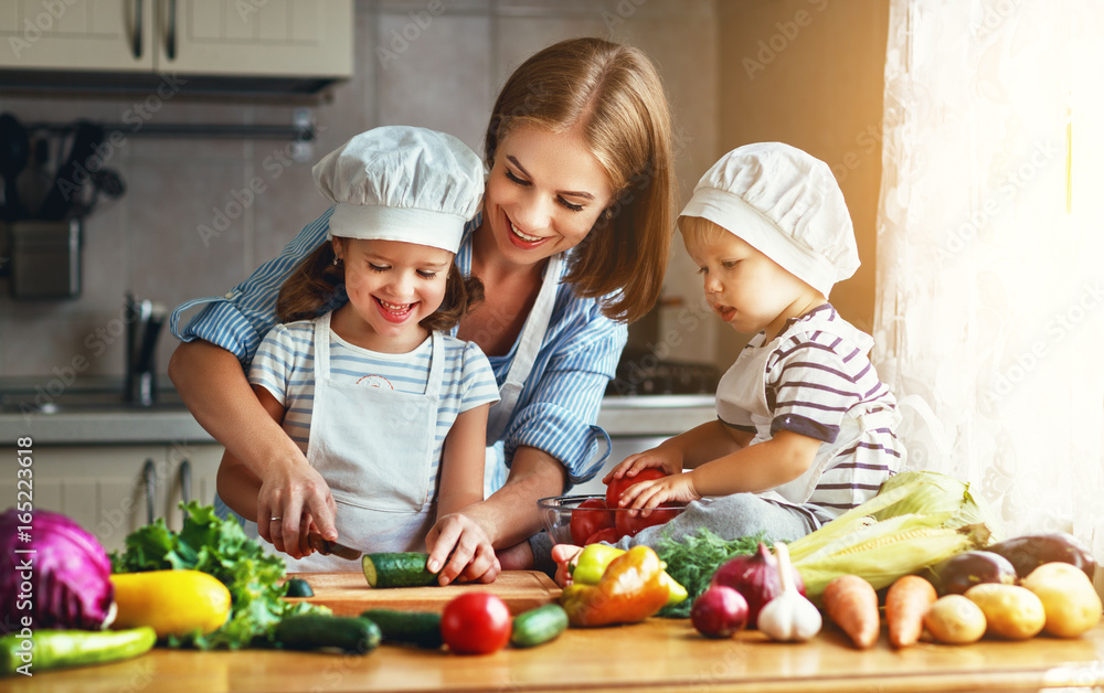 Healthy eating. Happy family mother and children prepares  vegetable salad - obrazy, fototapety, plakaty 