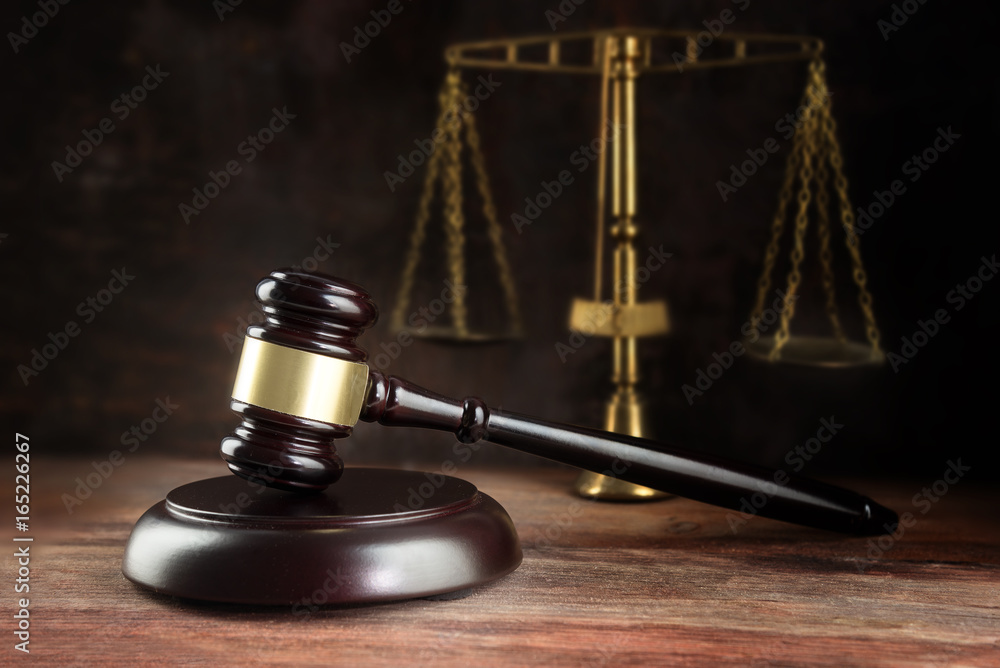 Judge gavel and scales on a wooden desk, symbol for balance and power in law and court, dark background with copy space Judge gavel and scales on a wooden desk, symbol for balance and power in law and court, dark background with copy space
