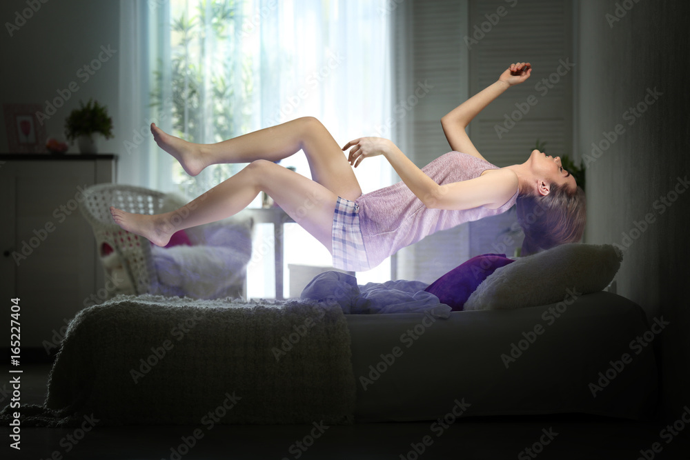 Sleep paralysis concept. Young woman levitating over bed Sleep paralysis concept. Young woman levitating over bed
