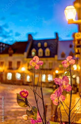 Closeup of fake cloth orchid flowers at night with bokeh background on illuminated European street