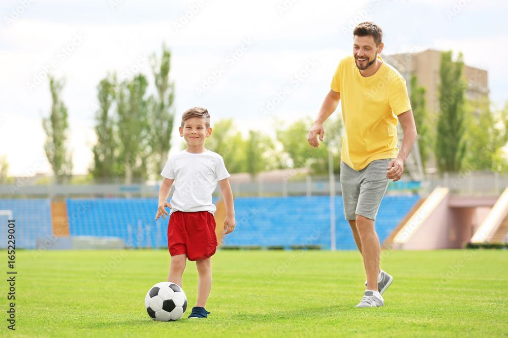 Dad and son playing football together in stadium Dad and son playing football together in stadium