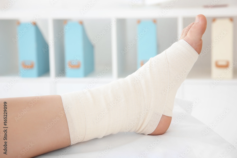 Young woman with bandaged leg in clinic, closeup Young woman with bandaged leg in clinic, closeup