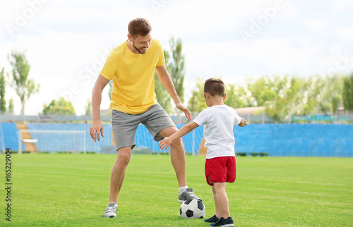 Dad and son playing football together in stadium