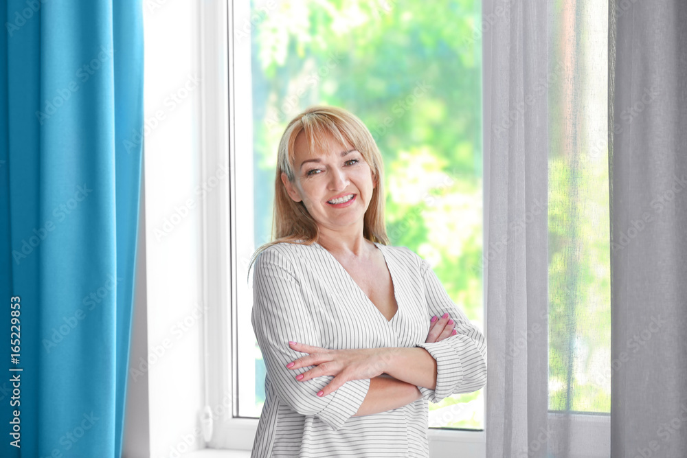 Attractive mature woman standing near window Attractive mature woman standing near window