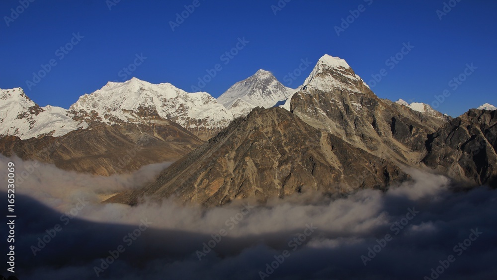 Fototapeta premium Above the clouds. High mountains Lobuche, mount Everest and Cholatse seen from the Gokyo valley.