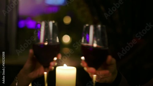 Couple in love holding hands and clink glasses during a romantic dinner.