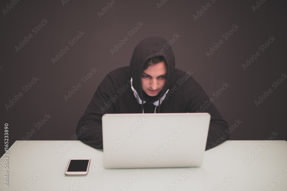 Hacker a sitting at a desk in the darkness stealing information Hacker a sitting at a desk in the darkness stealing information
