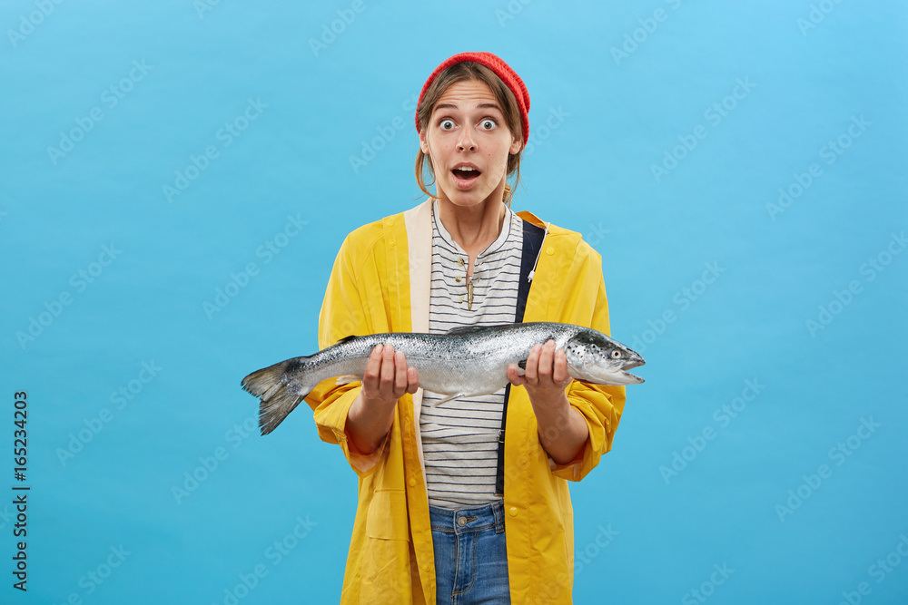 Astonished fisherwoman dressed casually while holding big fish being  surprised to catch so huge trout. Female angler offering to buy you her  catch at sea. People, hobby, fishing and recreation concept Stock