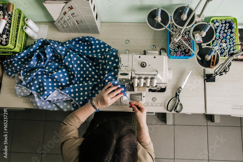 Female seamstress working at the sewing serger machine photo