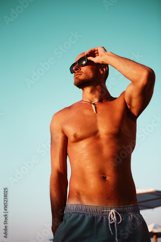 Fit handsome man sunbathing at the beach