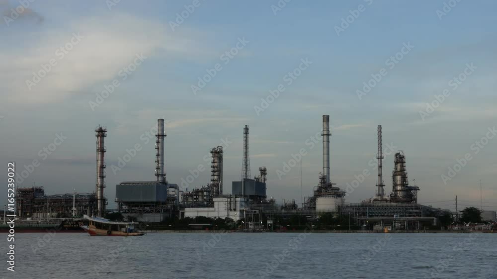 Time lapse. Cargo container ship, Carrier boat floating and moving in river with Oil Petrochemical energy plant background. Business Industry and Logistics shipping, maritime transportation concept
