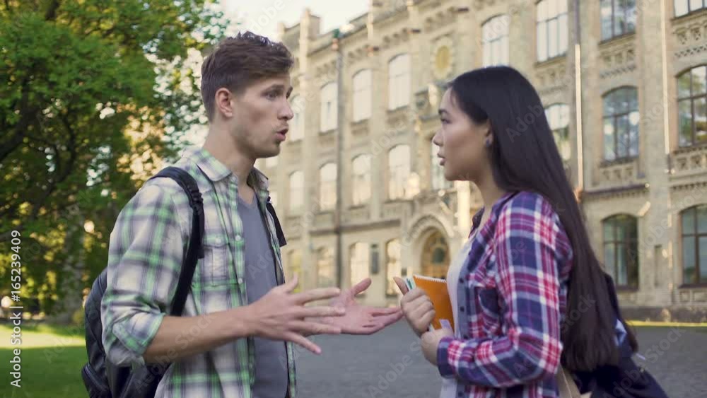 Multiracial students discussing test near campus, male and female talking Multiracial students discussing test near campus, male and female talking