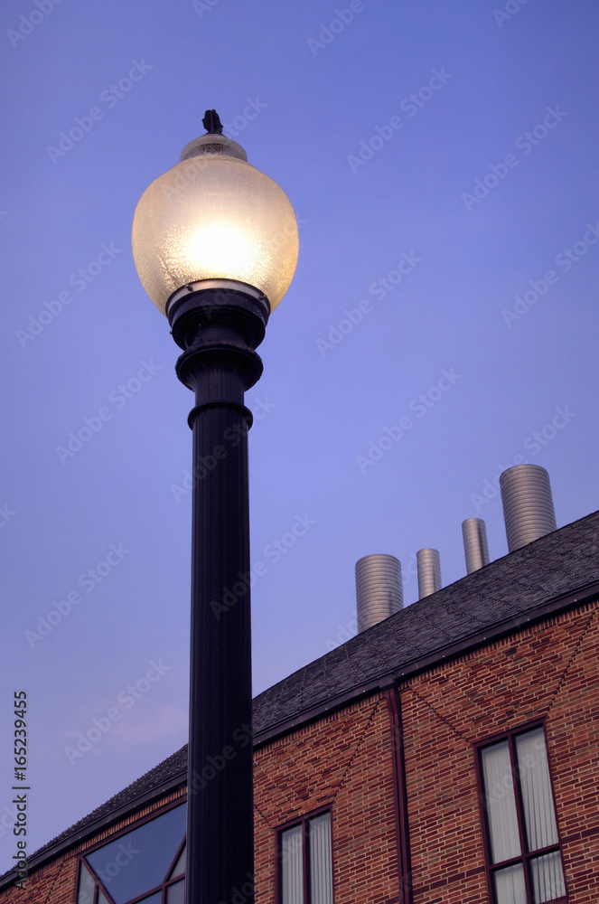 Lamp Post at Dusk by Modern Brick Building