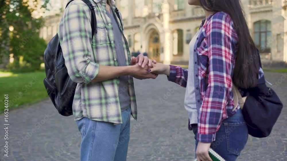 Young man stroking girlfriend's hand tenderly, student love, relationship Young man stroking girlfriend's hand tenderly, student love, relationship