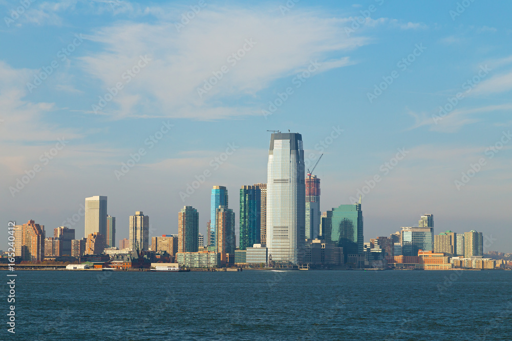 Panorama of Lower Manhattan from the water, New York, USA. Skyscrapers of Manhattan are illuminated by afternoon sun.