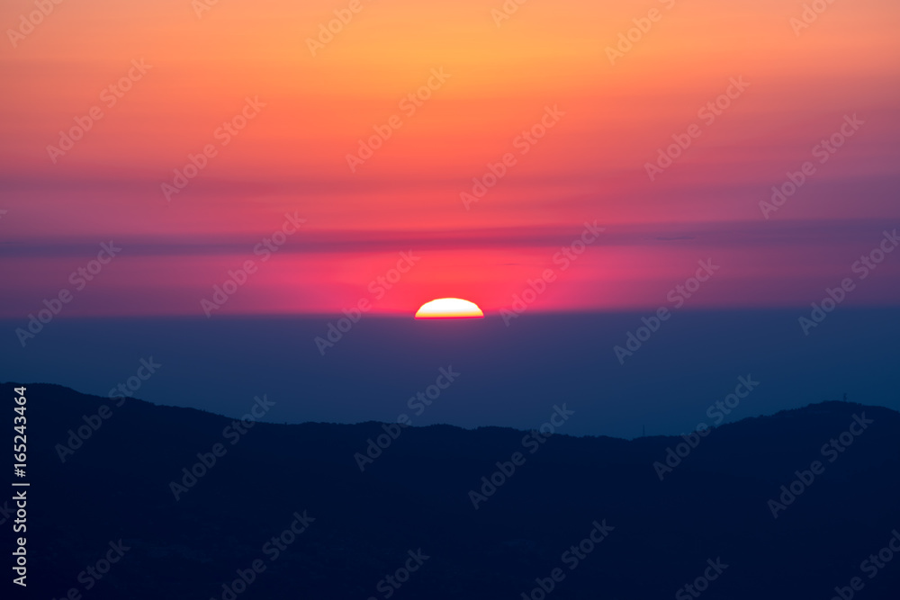 Obraz premium sun behind mountain layer during chage of light