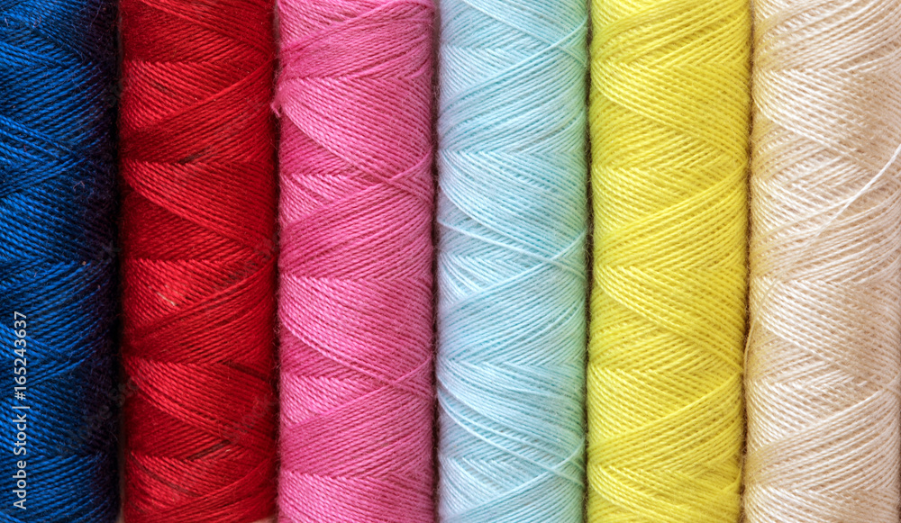 Close up multi color of the bobbins threads roll as background Close up multi color of the bobbins threads roll as background