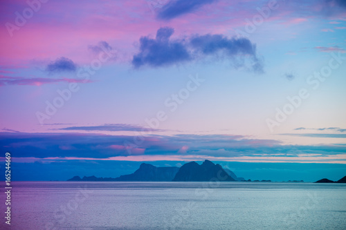 An island with a mountain on the horizon. Beautiful landscape, blue sky with clouds and sea. Wild nature Norway, seascape.