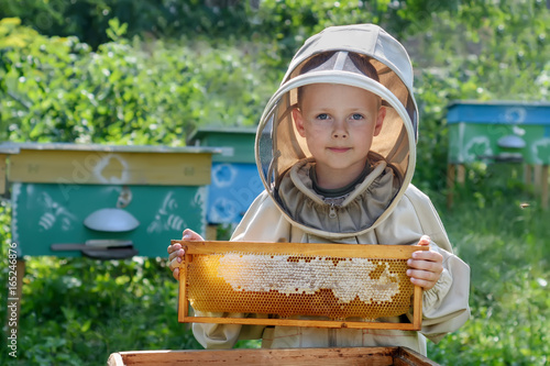 The boy beekeeper holds in his hands a honeycomb with fresh honey. Apiculture. Fresh honey.