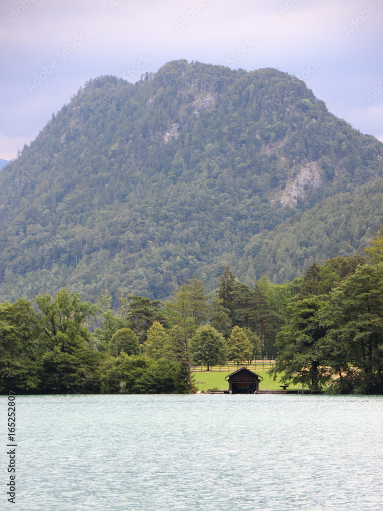 Fototapeta premium Boathouse with Mountain Background at Blue Water Sea