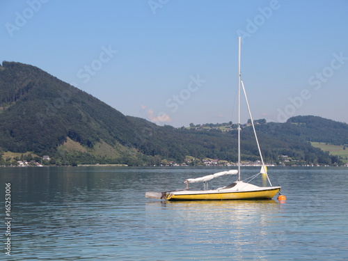 Yellow Sailboat on Blue Lake with Mountain Background