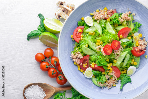 Salad with fresh vegetables and tuna. On a wooden background. Top view. Free space for your text.