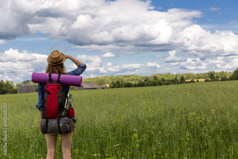 Young woman with backpack hiking in the countryside. Stress free travel concept. 