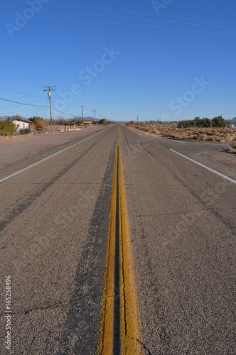 Center view of the famous Road 66 with straight yellow middle line and electric poles