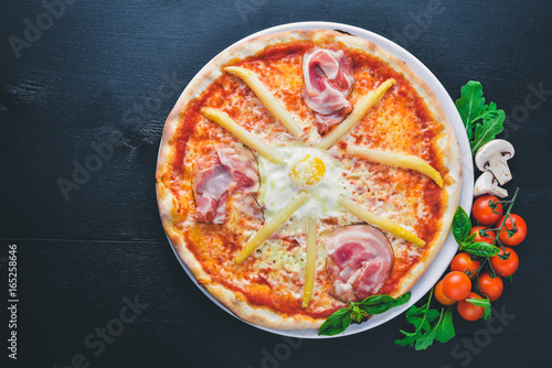 Pizza with asparagus and bacon. On a wooden background. Top view. Free space for your text.