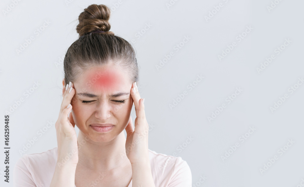 Fototapeta premium Portrait of female isolated on grey background suffering from severe headache, pressing fingers to temples, closing eyes in order to relieve pain