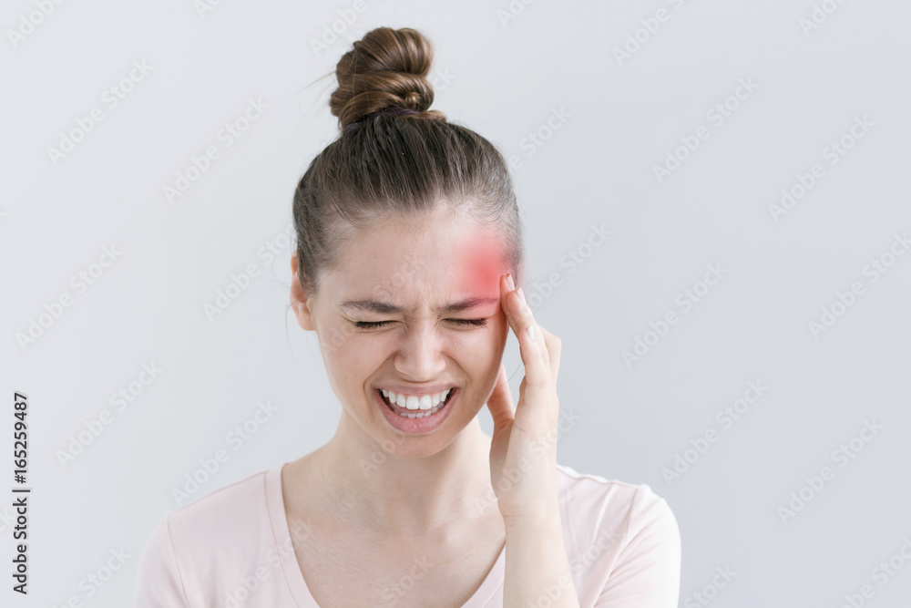 Beautiful young woman squeezing face because of strong pain, putting one hand to head, screaming and curving mouth in suffering from migraine Beautiful young woman squeezing face because of strong pain, putting one hand to head, screaming and curving mouth in suffering from migraine